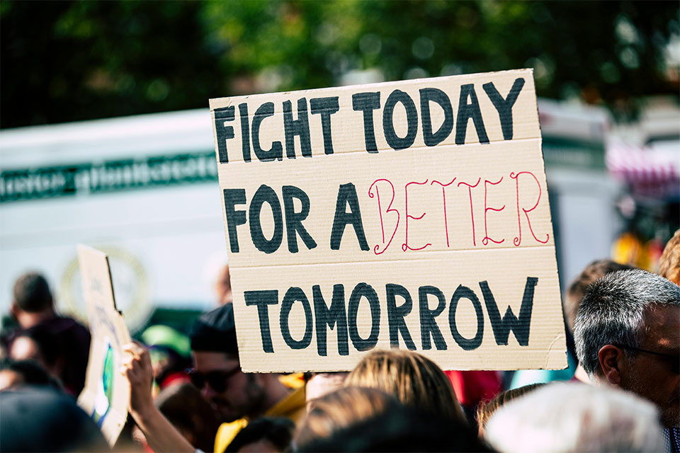 demonstrator holding a hand-drawn cardboard sign